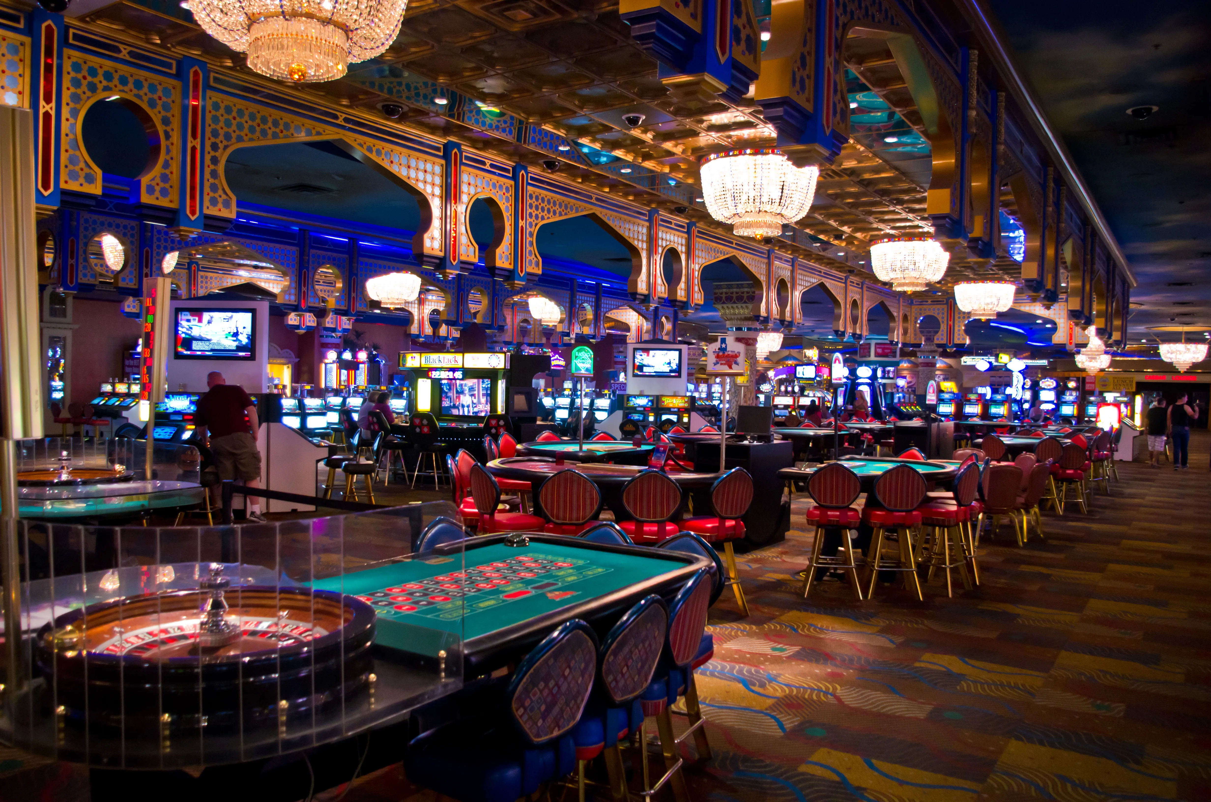 Salle de casino illuminée, avec machines à sous et tables de jeu