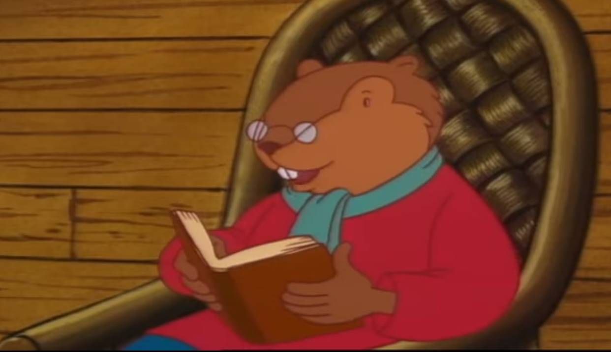 Le Père Castor, personnage de dessin animé, lit une histoire assis dans un fauteuil en osier